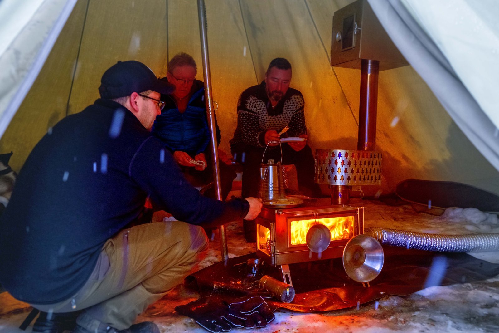A person safely using a camping oven on a fire-resistant mat inside a tent.
