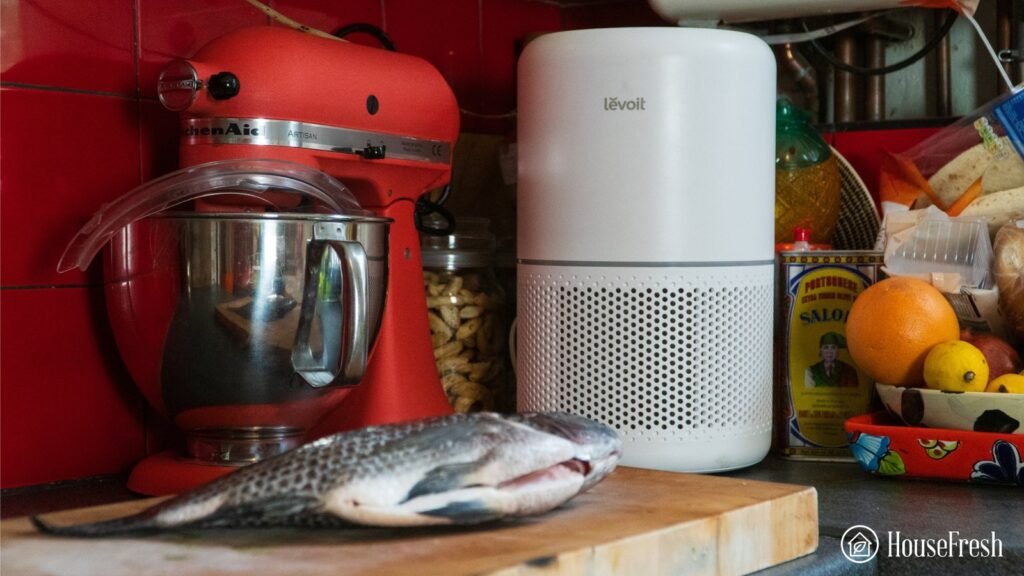 A modern air purifier placed on a kitchen counter to remove cooking smells.