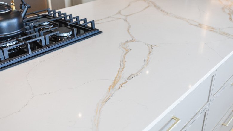 A luxurious kitchen showcasing Calacatta Gold quartz countertops and a matching stone backsplash.