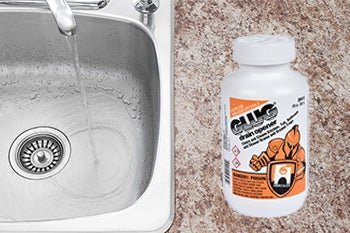 Professional drain cleaner bottle beside a kitchen sink filled with standing water.