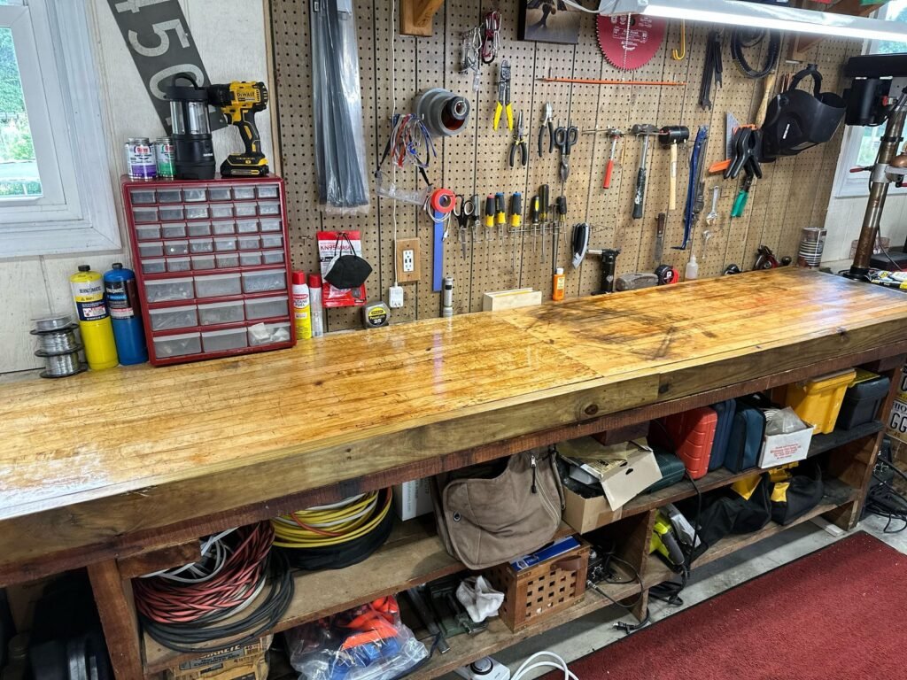 A smooth, oil-finished oak butcher block workbench surface in a sunlit workshop.
