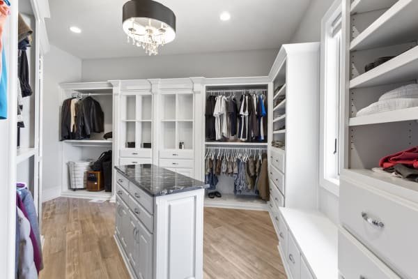 A modern walk-in closet featuring durable luxury vinyl flooring with a natural wood aesthetic.
