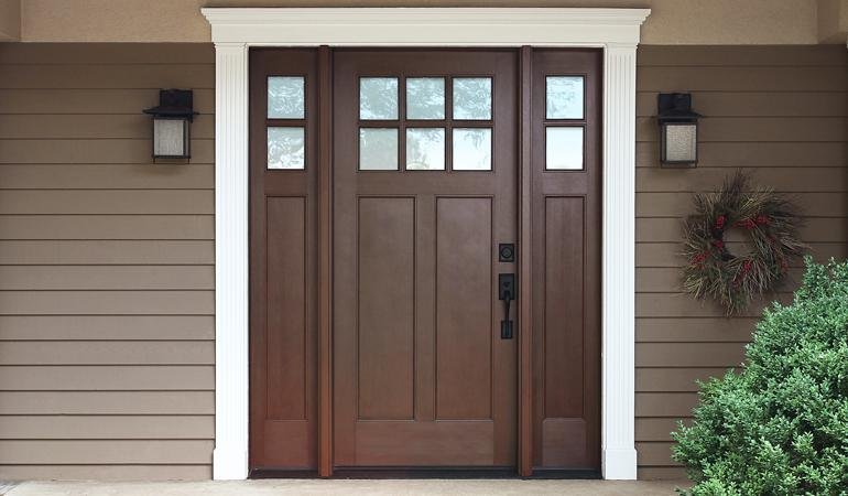 Applying rich wood-toned gel stain to a textured fiberglass door in soft light.