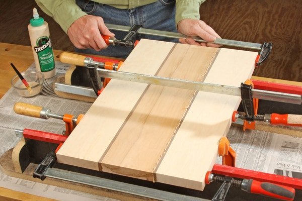 A bottle of wood glue sitting next to a handcrafted wooden cutting board.
