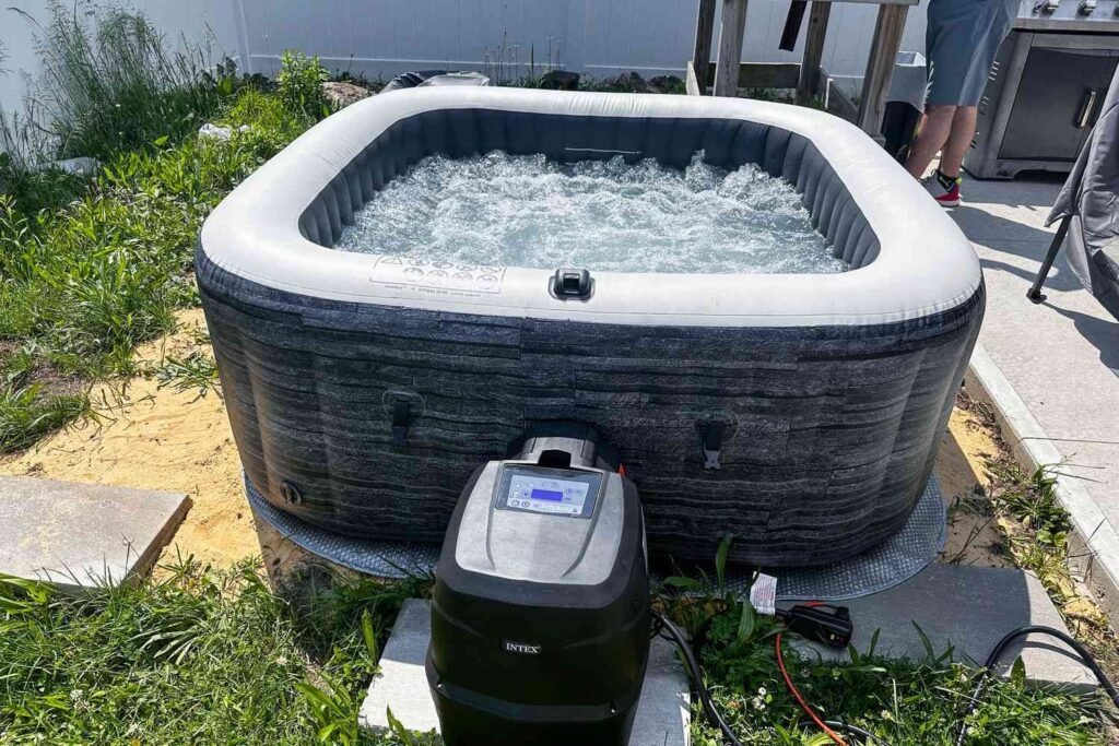 A steaming inflatable hot tub sits on a snowy patio during winter.