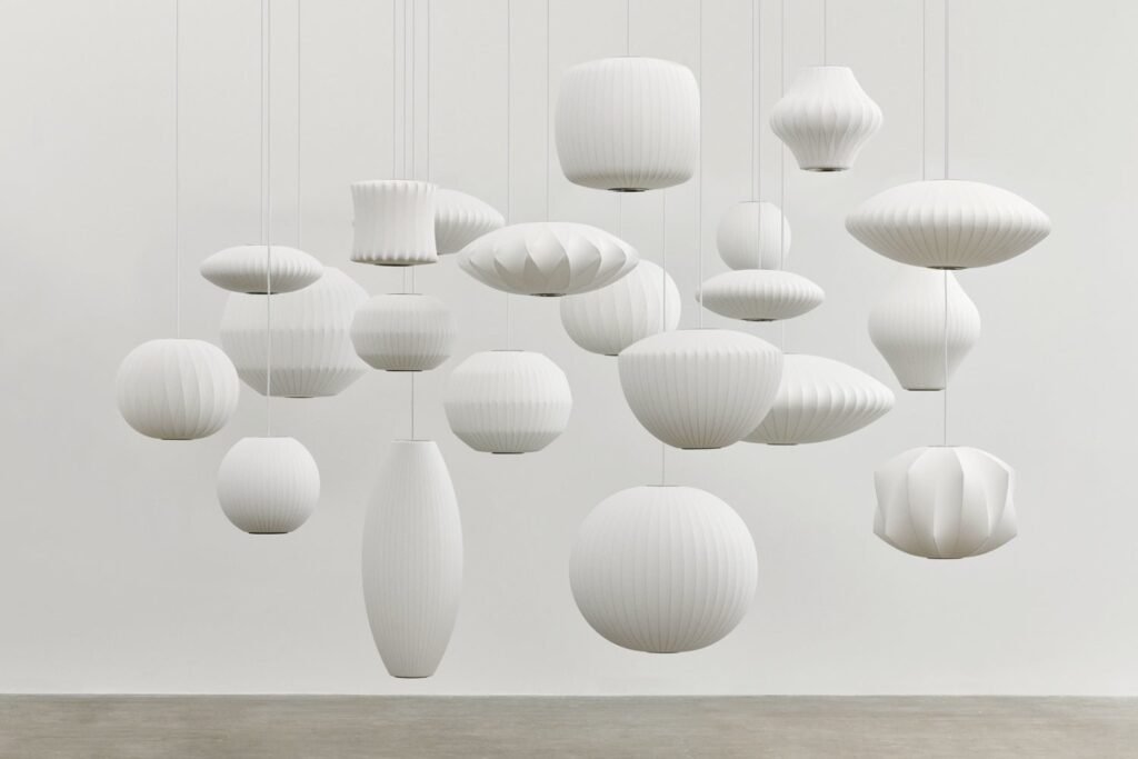 A glowing Nelson bubble lamp hangs elegantly in a modern, sunlit living room.