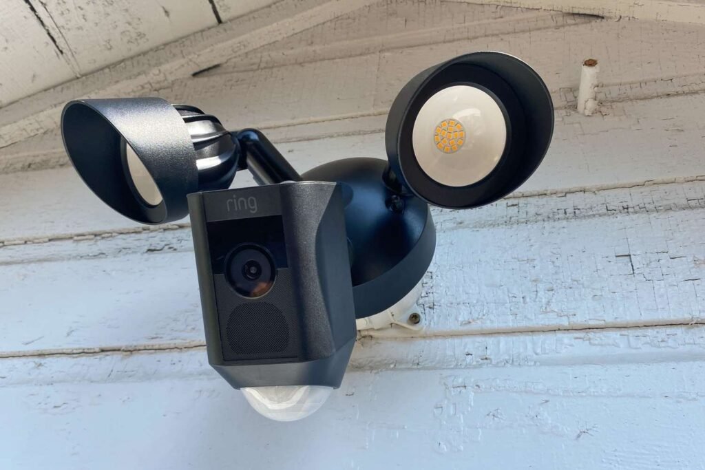 A modern motion sensor outdoor light fixture glows warmly against a dark house wall.