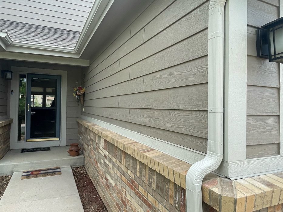 A professional paint roller applying fresh coating to textured LP SmartSide exterior siding.