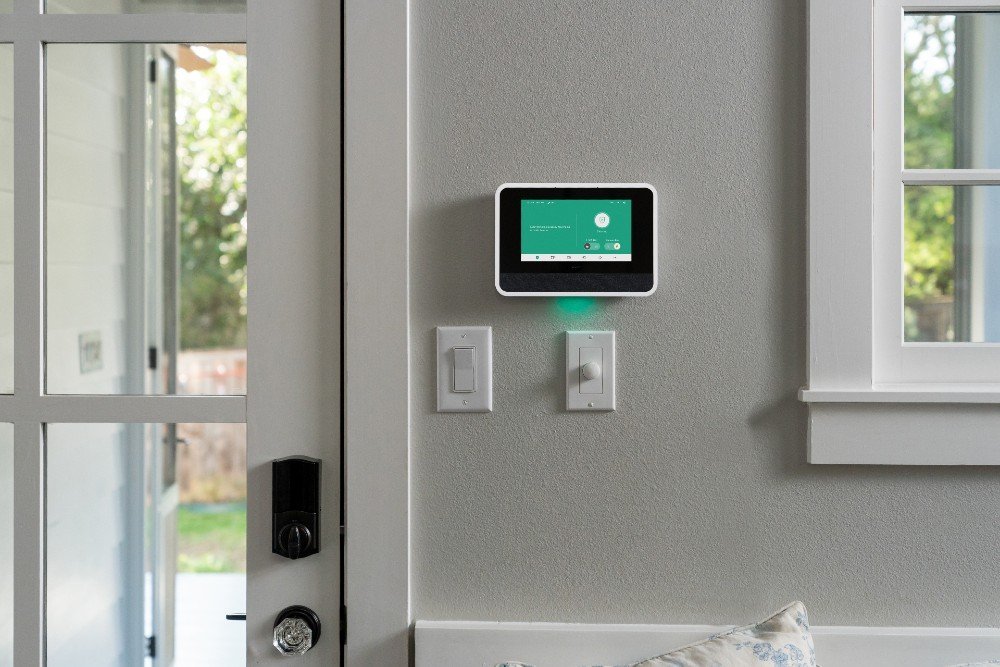 A modern living room featuring a wall-mounted tablet for a smart house system.