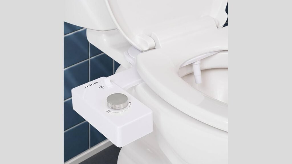 A modern white toilet seat with a bidet attachment in a bright bathroom.
