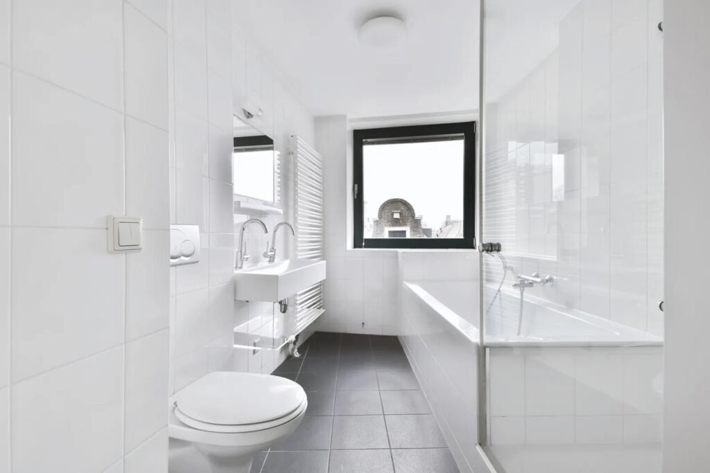 A modern toilet seat being installed in a clean, bright, contemporary rental bathroom.