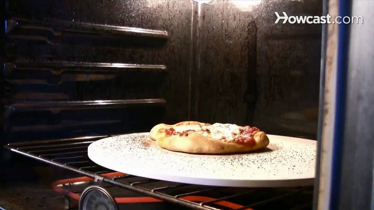 A home cook holding a pizza stone in a bright modern kitchen.