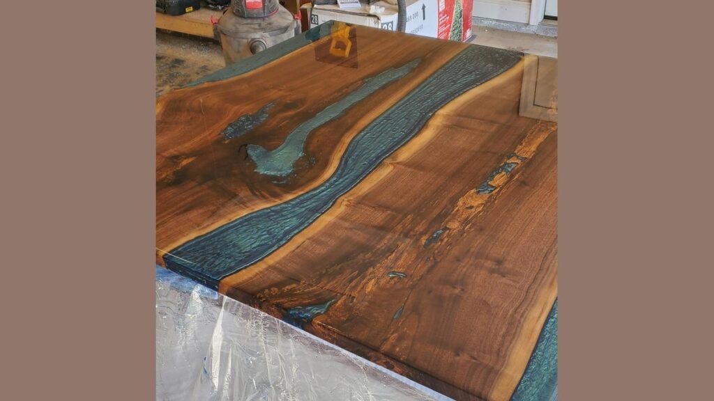 A craftsman carefully applies wood sealer to a walnut slab before epoxy application.
