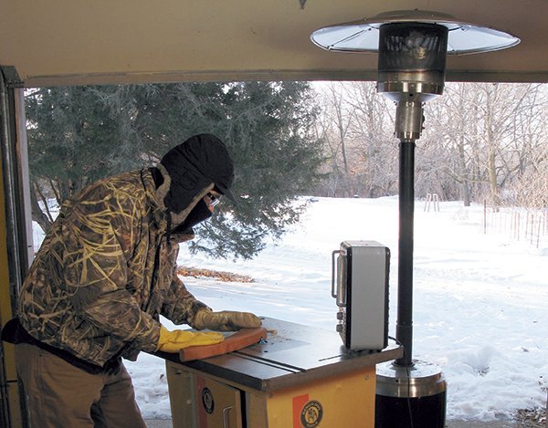 A portable heater warms a well-organized wood workshop during a cold winter day.