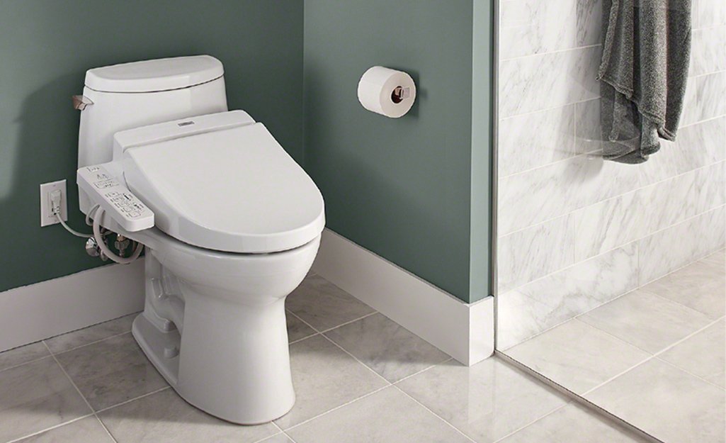 An installer measuring the distance between a wall outlet and a toilet base.