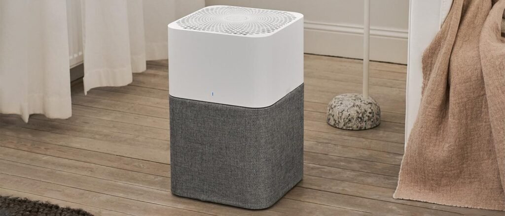 A modern Blueair Blue 211 air purifier placed in a stylish, sunlit living room.