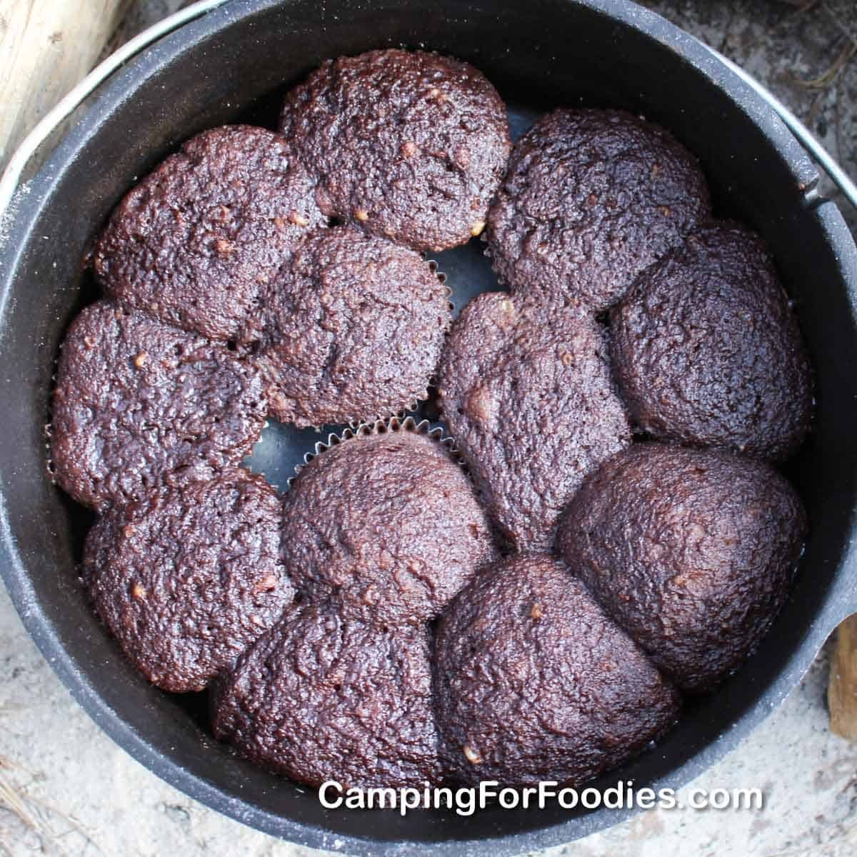 A portable camping oven sits on a gas burner ready for baking cakes.