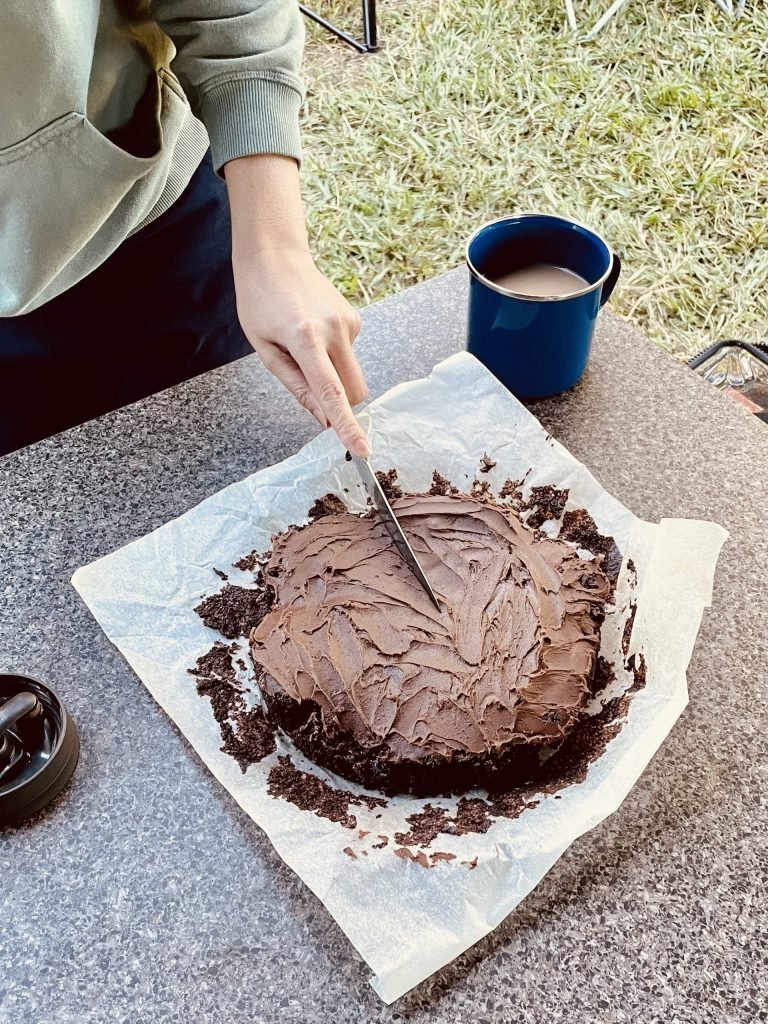 Adjusting a baking pan inside a camping oven to manage heat distribution.