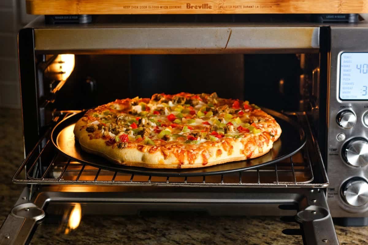 A modern outdoor pizza oven sits on a sleek kitchen counter.