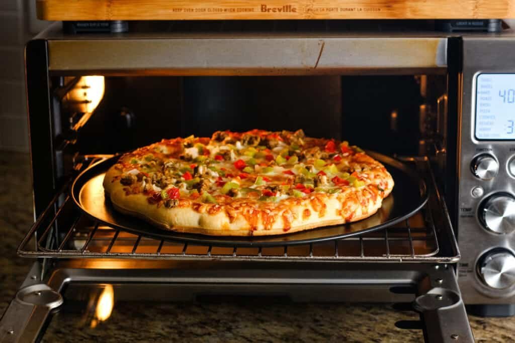 A burnt pizza crust and a thermometer on a wooden table.