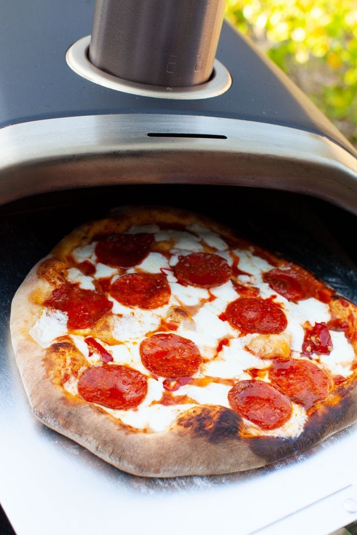A perfectly baked pizza crust with charred edges on a cooling rack.