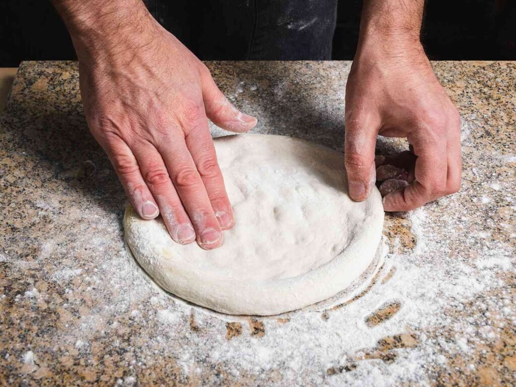 A home pizza oven with raw dough ready for cooking on a patio.