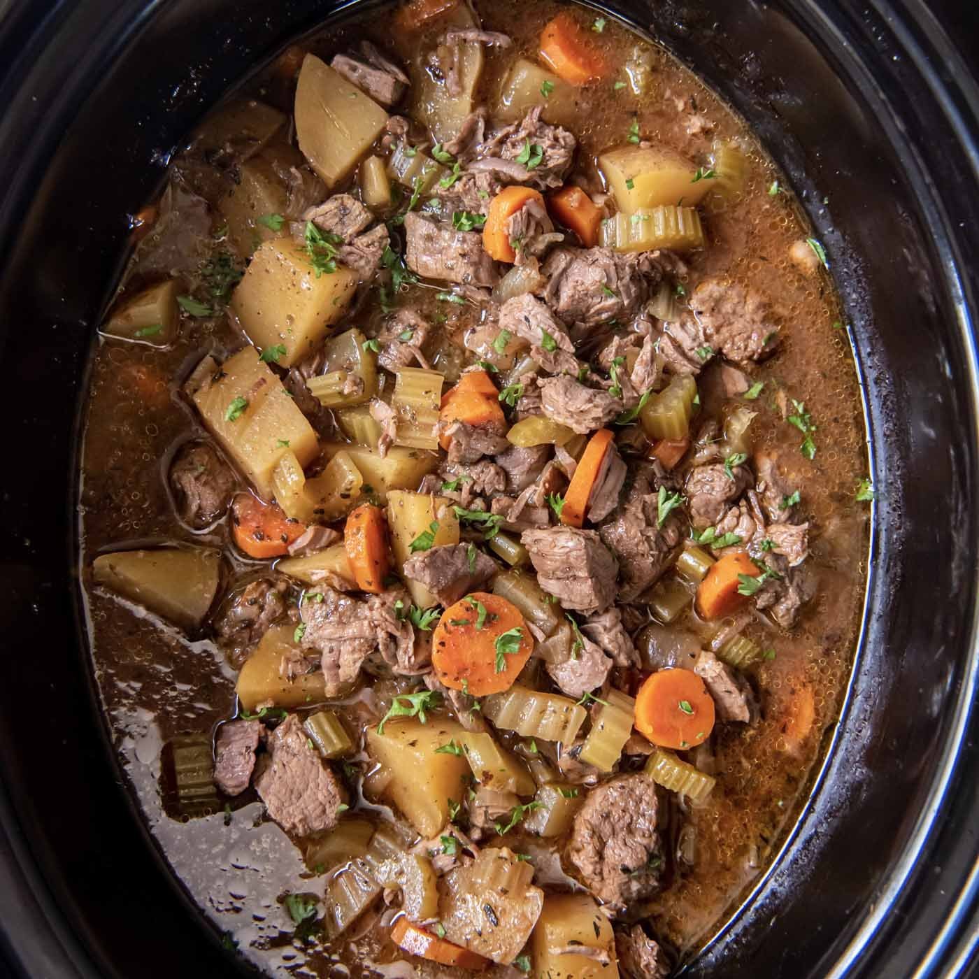 A digital meat thermometer checks the internal temperature of meat in a slow cooker.