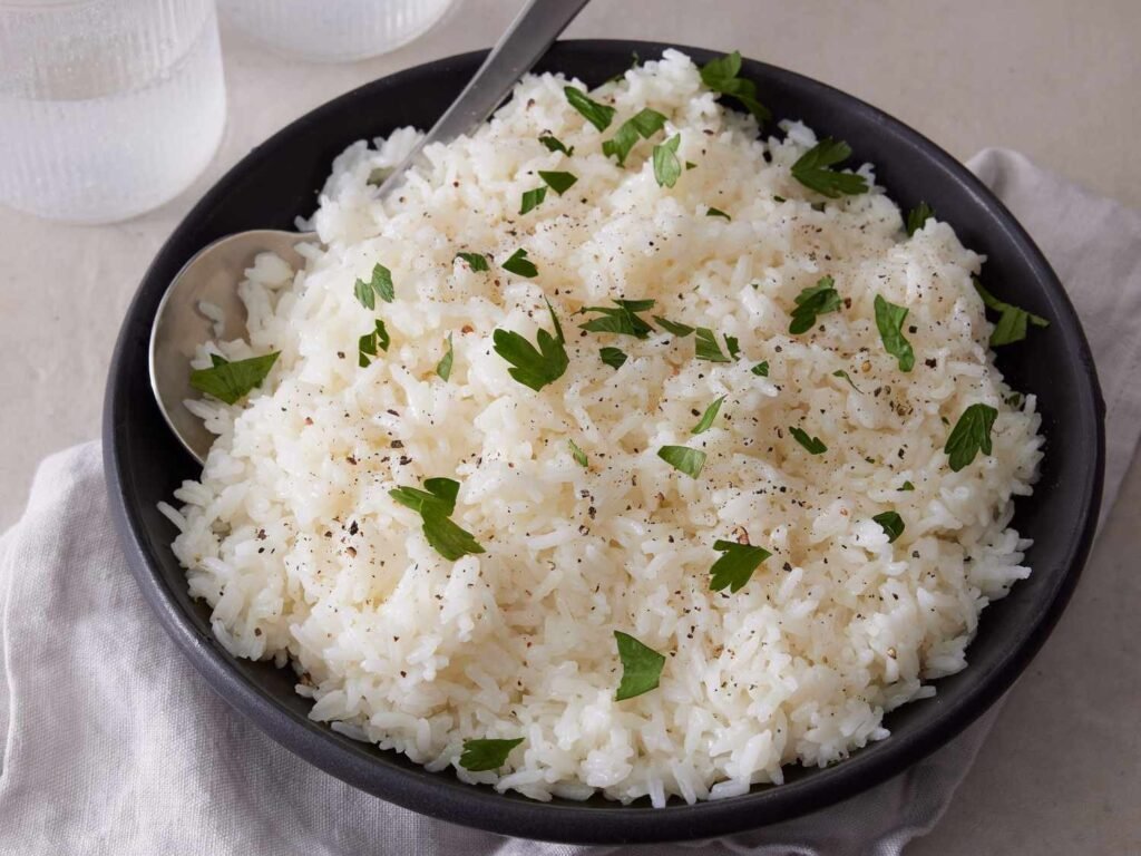 A ceramic dish of perfectly cooked rice prepared using an oven cooking method.