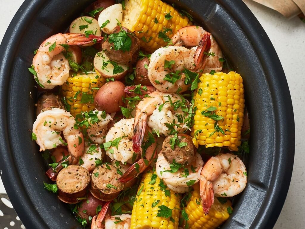 A variety of fresh seafood arranged next to a modern kitchen slow cooker.