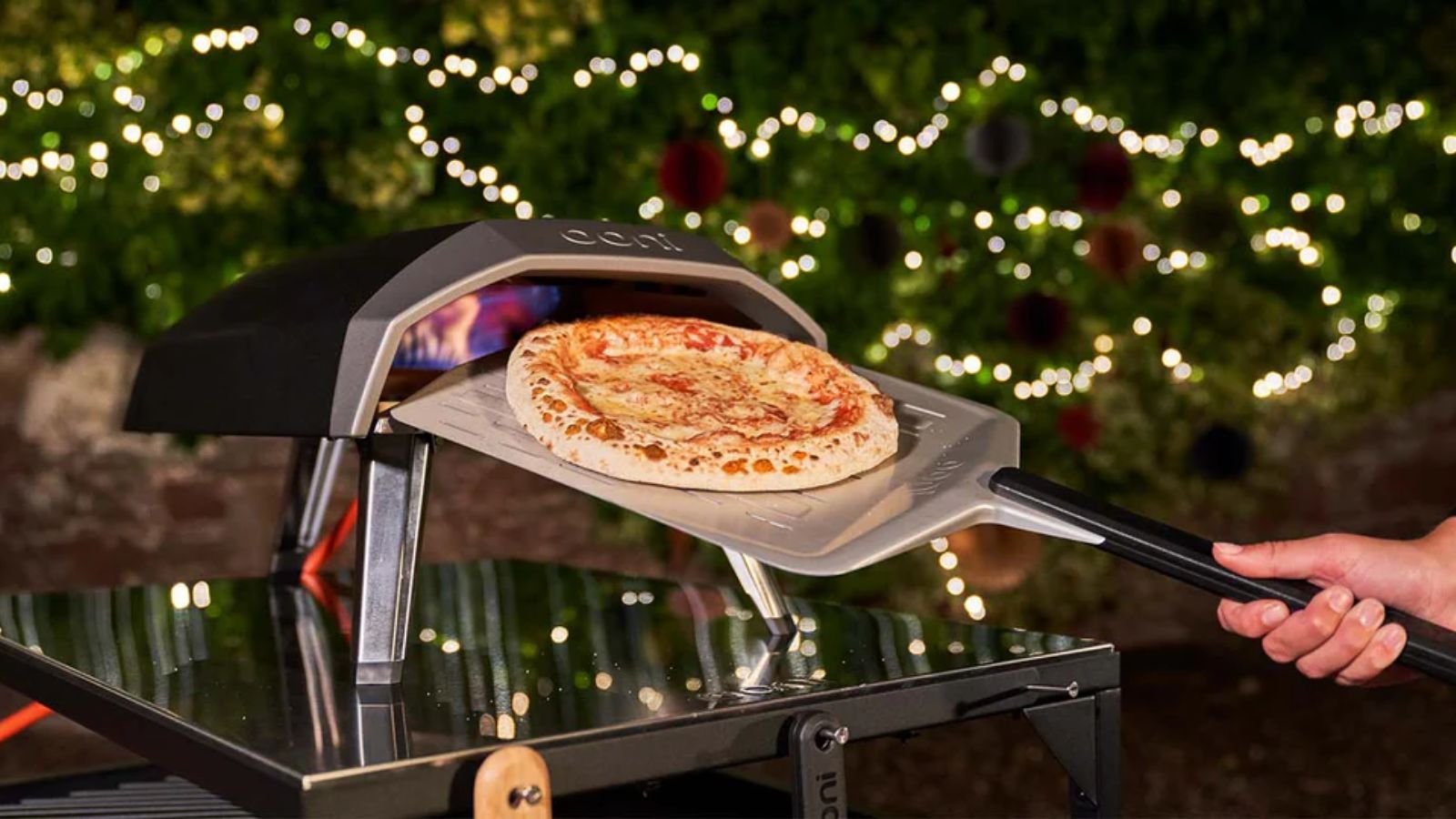 Adding firewood to an outdoor brick pizza oven on a cold winter day.