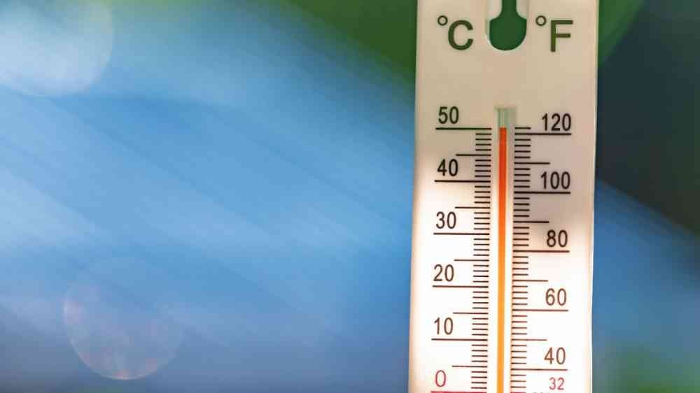 A technician troubleshooting a failed outdoor thermometer with new batteries and repair tools.