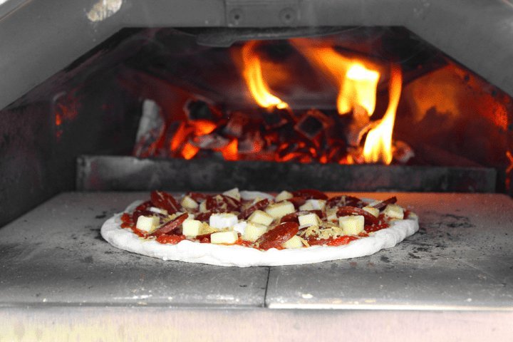 Adjusting the temperature dial on a propane powered outdoor pizza oven.