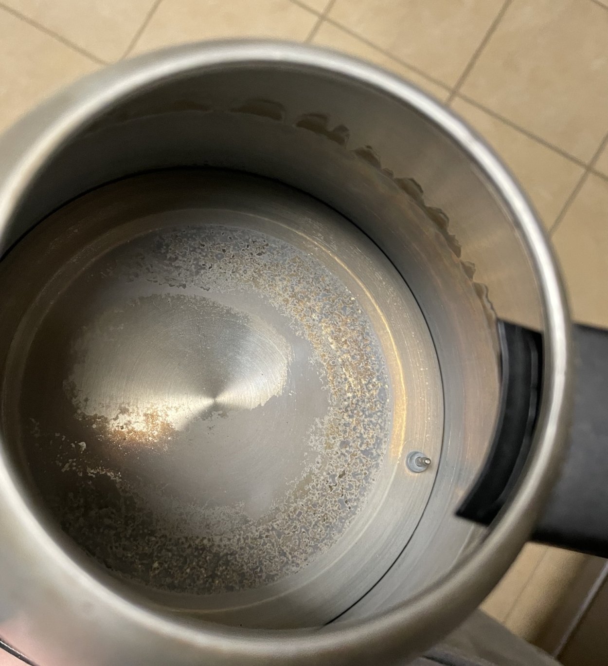 A person reaches for their electric kettle in a busy morning kitchen.