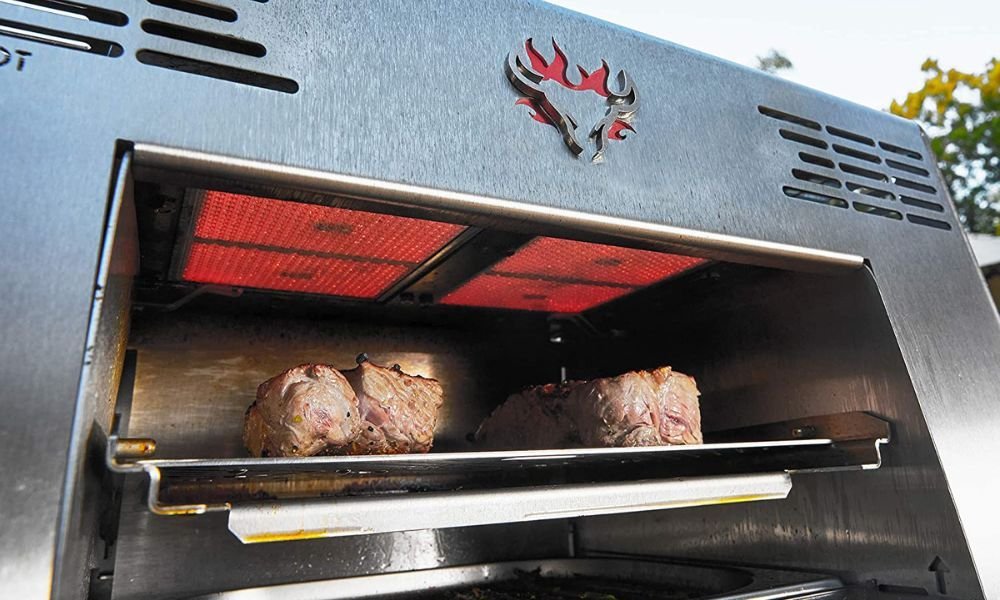 Infrared elements searing a piece of meat inside a modern kitchen oven.