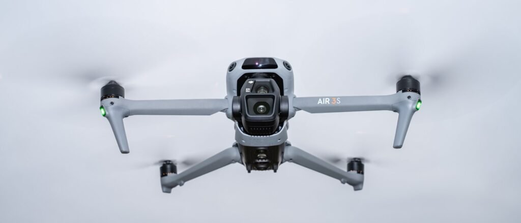 The DJI Air 3S drone sits on a cliff edge overlooking mountains.