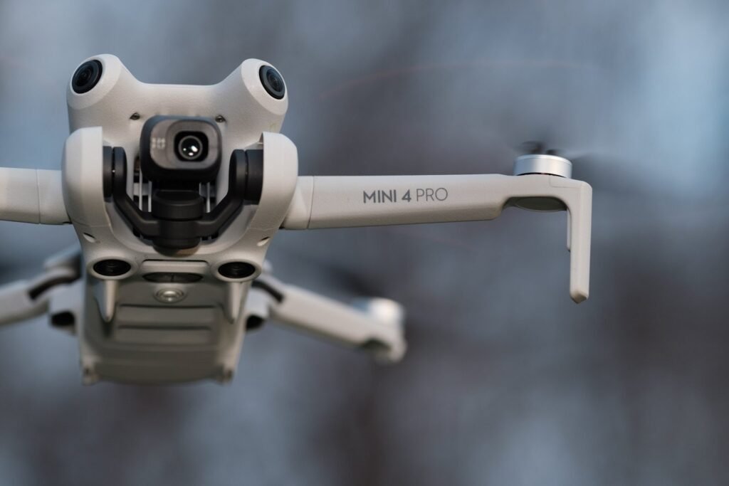 The DJI Mini 4 Pro drone sits on a rocky cliffside overlooking mountains.