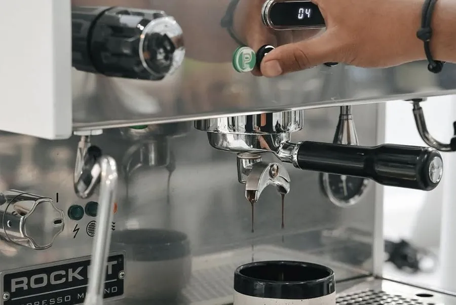 A French press and pour-over dripper on a table near an unused espresso machine.