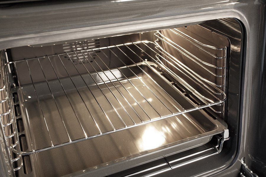 A stainless steel broiler pan sitting on a clean wooden kitchen counter.