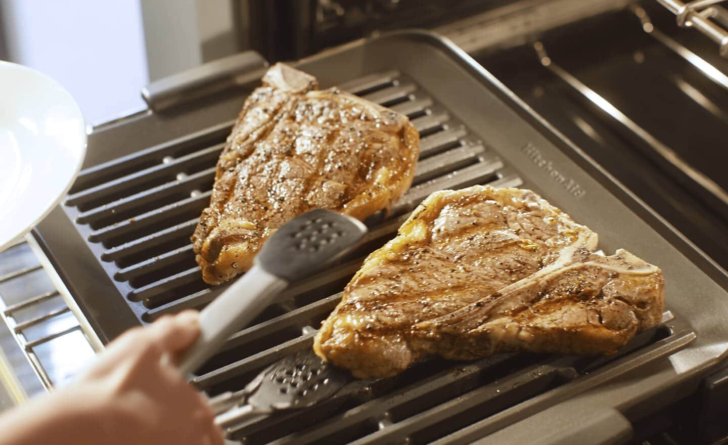 Hands adjusting an oven rack to a lower position for better cooking.