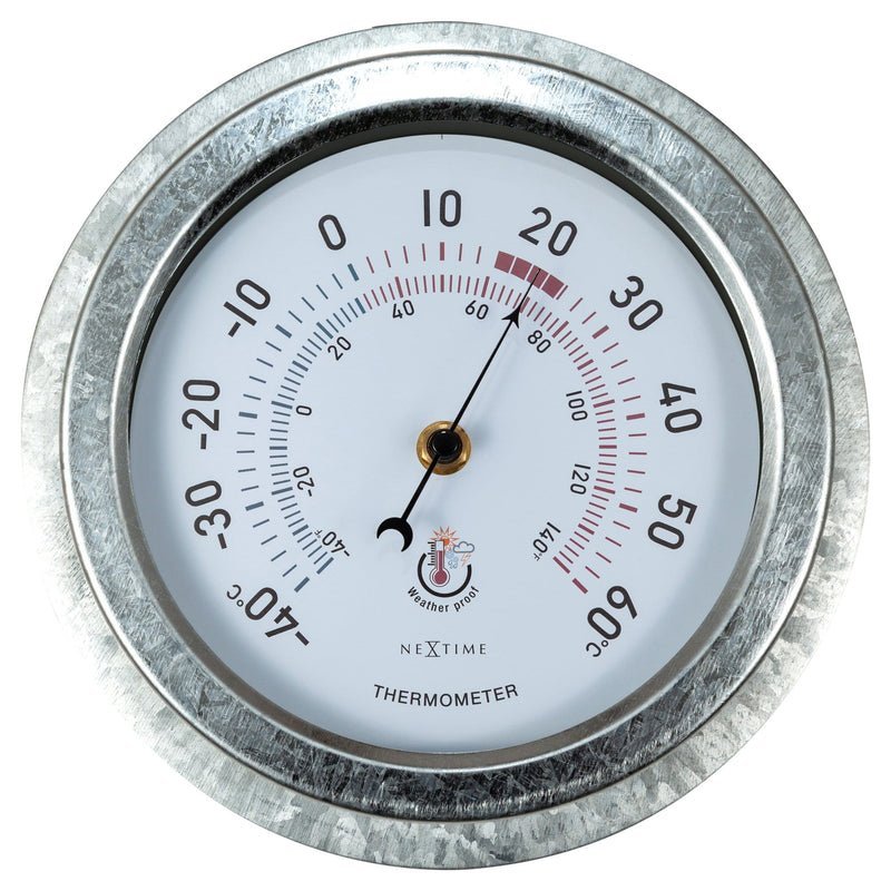 A gardener holds a foggy outdoor thermometer with condensation trapped inside the plastic casing.