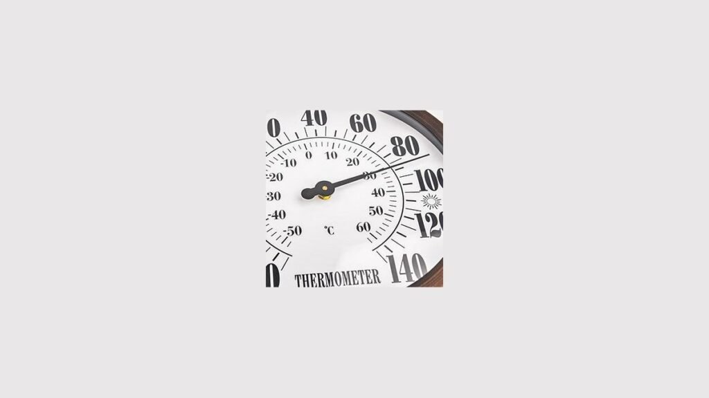 A clear outdoor thermometer mounted on a garden fence showing precise temperature readings.
