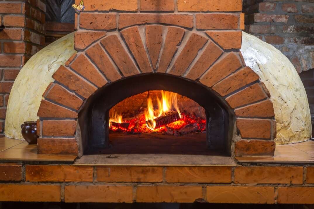 A perfectly charred pizza crust baking inside a hot stone oven.