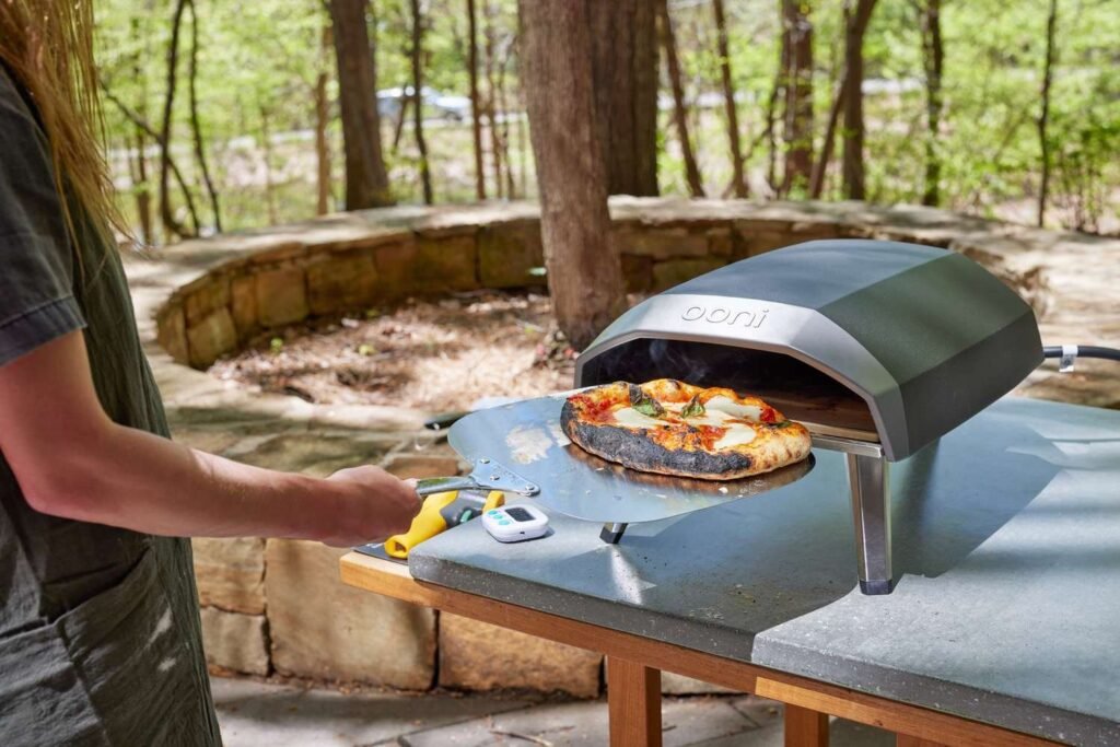 A modern outdoor pizza oven glowing in the warm light of sunset.