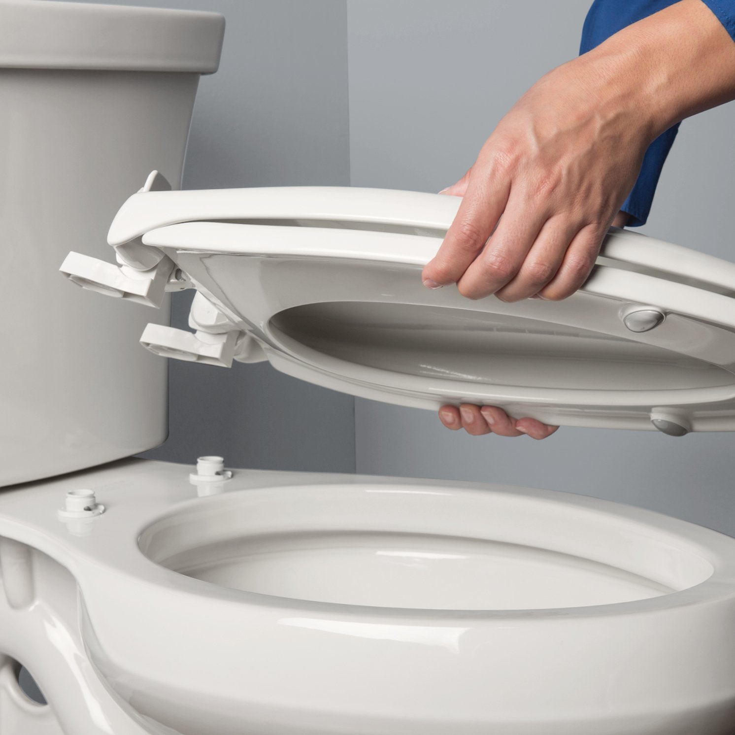 A cotton swab cleaning grime from the metal hinge of a toilet seat.