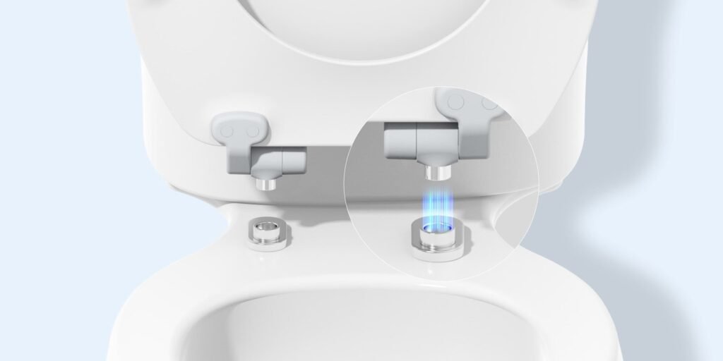 Close-up view of clean toilet seat hinges on a white porcelain toilet bowl.