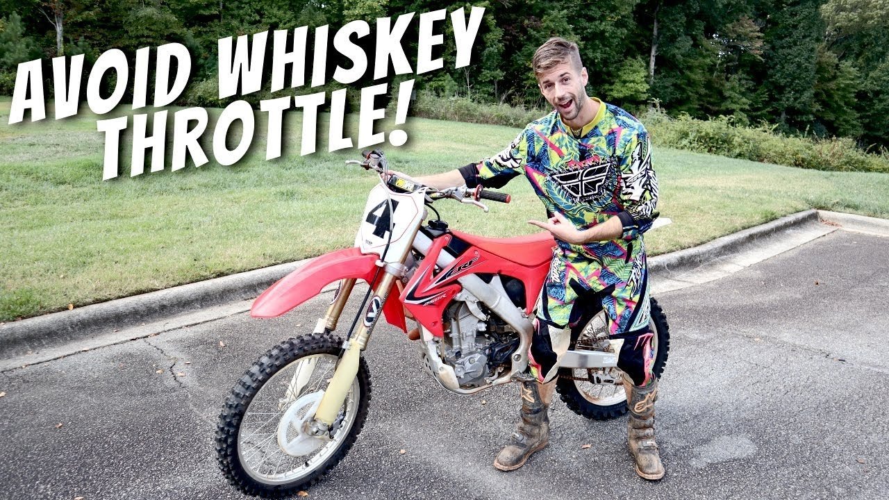 A dirt bike rider studies a map while taking a break on a hill.