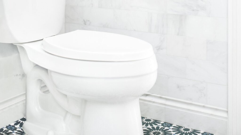 A close-up view of a modern toilet seat hinge in a clean bathroom.