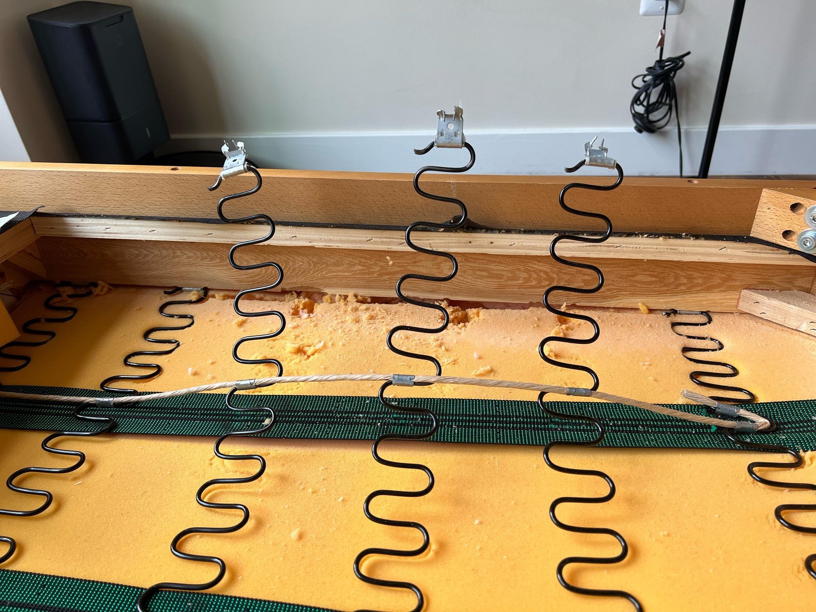 A broken mounting clip causes a sagging spring under a wooden chair.