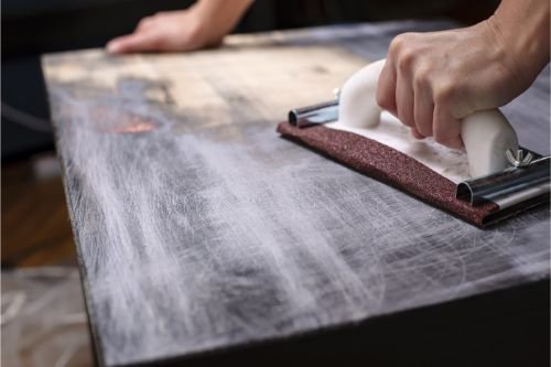 Using a furniture marker to blend a scratch on dark wood furniture.
