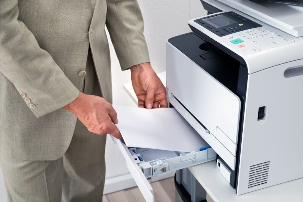 A person carefully preparing paper to load into a modern home printer.